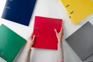 mains qui saississent un classeur rouge