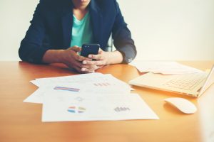 Personne analysant des documents financiers et des graphiques devant un ordinateur portable